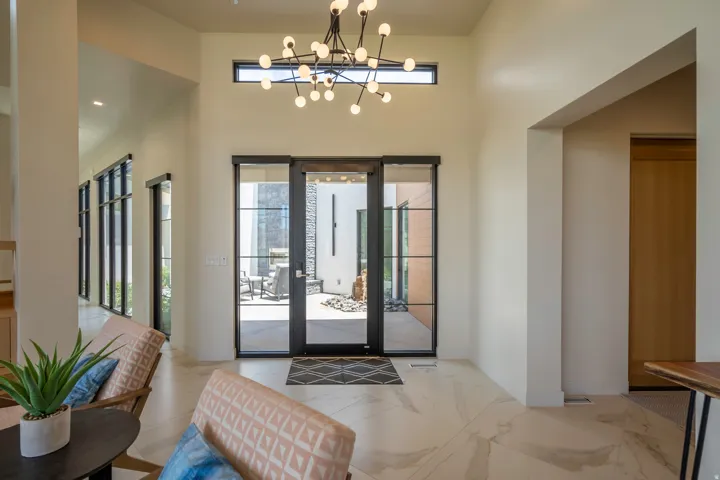 Foyer entrance featuring hanging lights, light marble finish floors, and a high ceiling