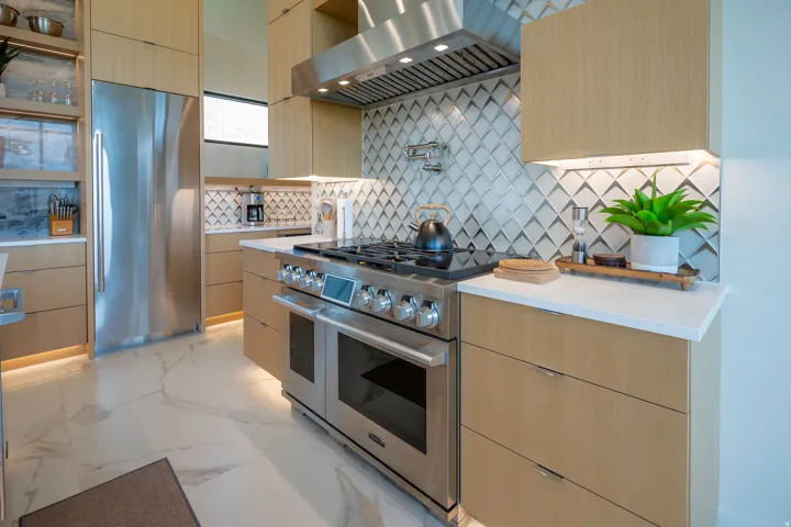 Kitchen featuring extractor fan, light wood finish cabinetry, high end appliances, modern cabinets, and light stone countertops