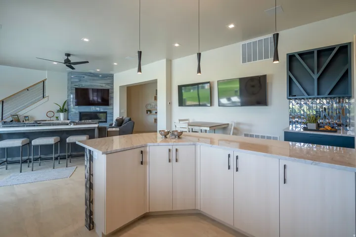 Kitchen with open floor plan, light stone countertops, ceiling fan, a fireplace, and hanging light fixtures