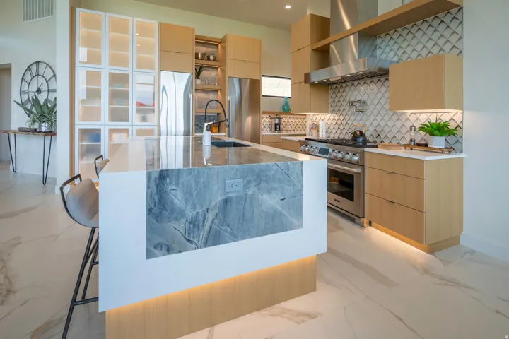 Kitchen with light marble finish flooring, light wood finish cabinets, light stone countertops, and high end appliances