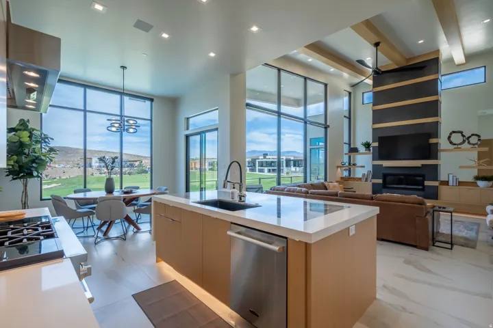 Kitchen with modern cabinets, light stone counters, a kitchen island with sink, stainless steel appliances, and range hood
