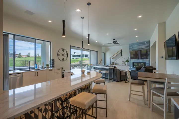 Kitchen featuring light stone countertops, pendant lighting, stainless steel dishwasher, ceiling fan, and modern cabinets
