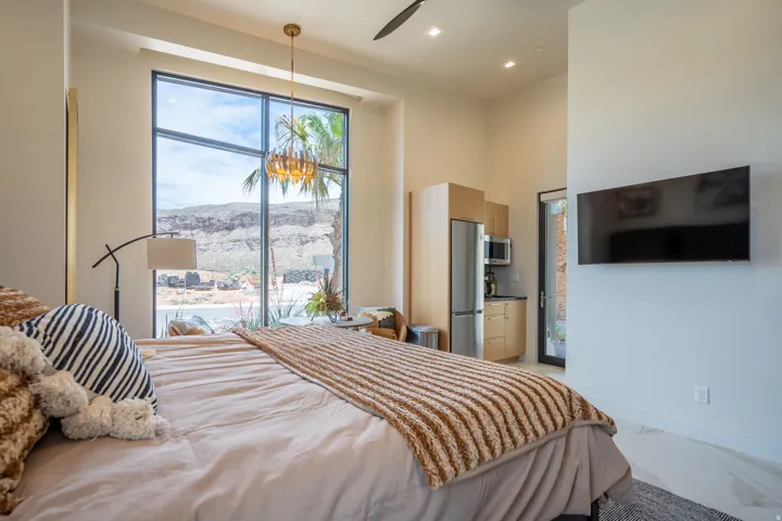 Bedroom featuring a high ceiling, freestanding refrigerator, multiple windows, recessed lighting, and a ceiling fan
