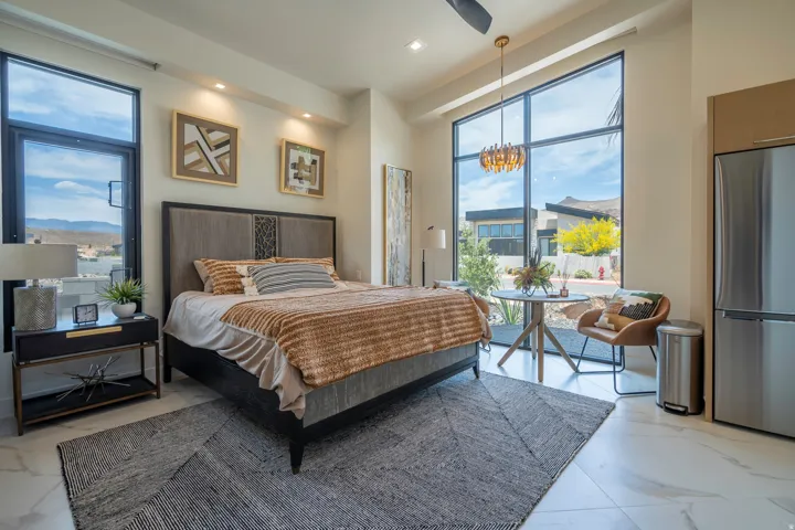 Bedroom with freestanding refrigerator, light marble finish floors, access to exterior, and ceiling fan