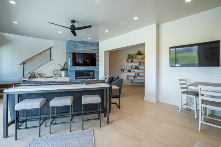 Kitchen featuring a tile fireplace, a ceiling fan, open floor plan, recessed lighting, and a breakfast bar