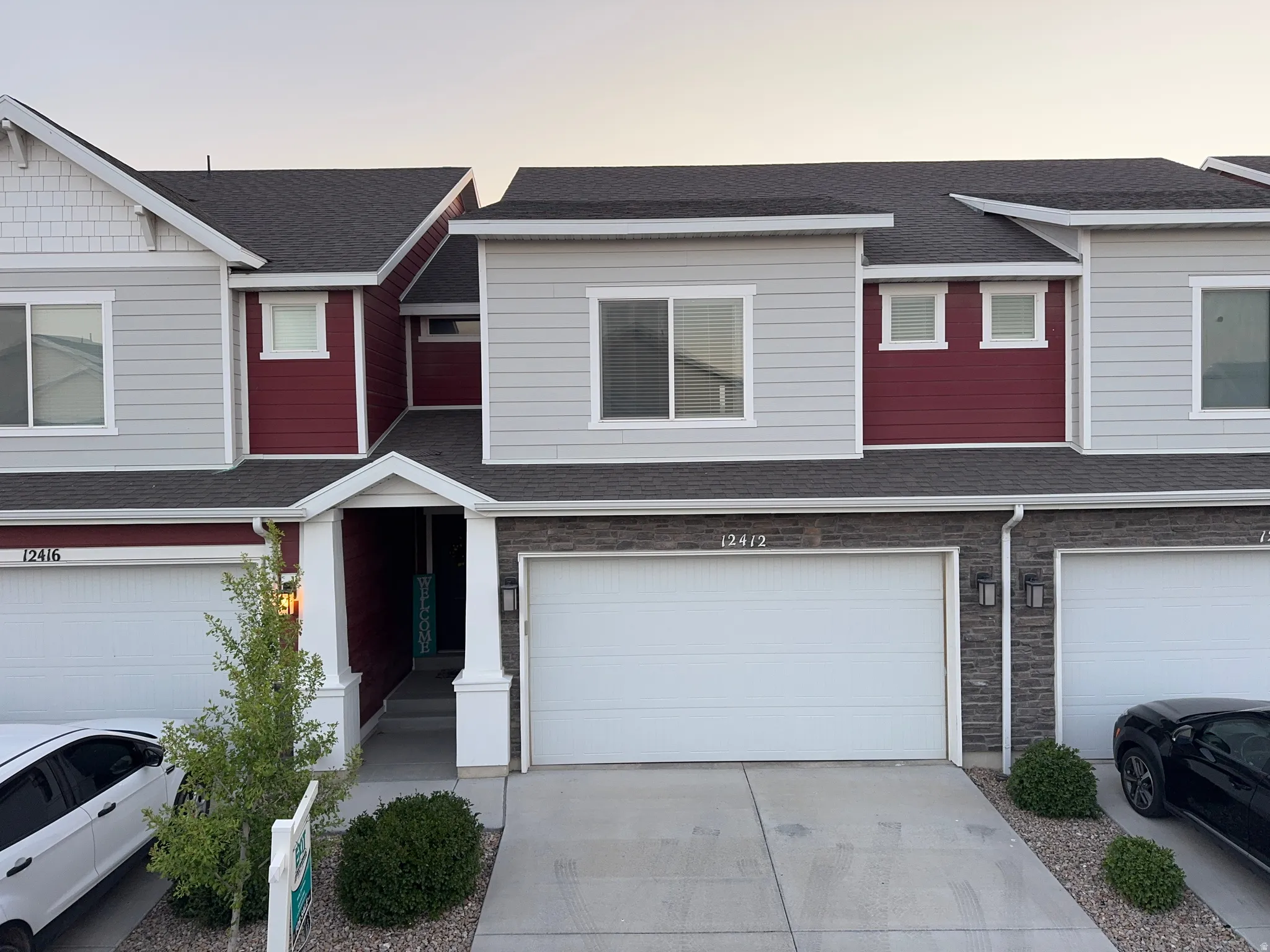 Contemporary townhome facade featuring gray siding, dark red accents, and white trim