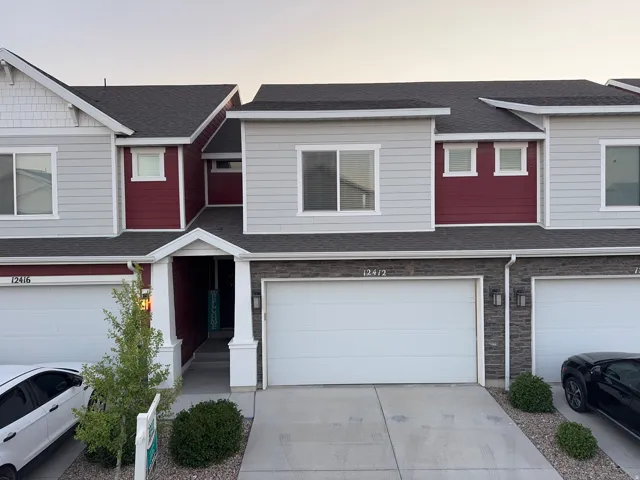 Contemporary townhome facade featuring gray siding, dark red accents, and white trim