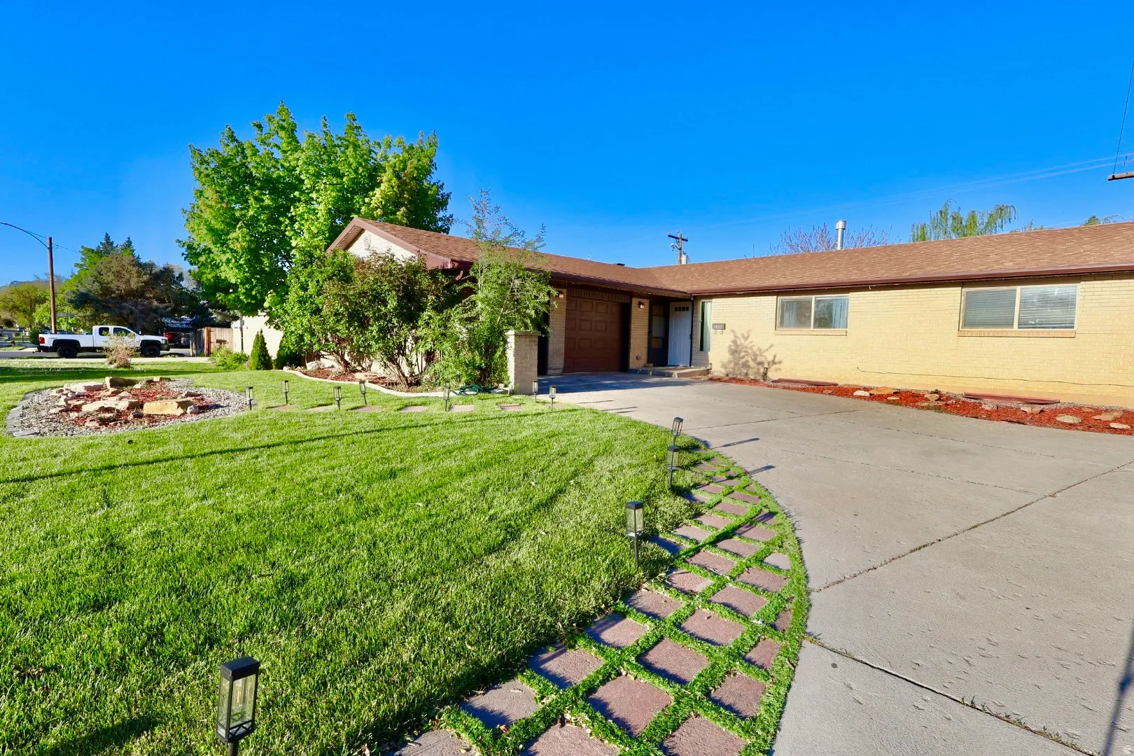 Ranch-style home with a garage, concrete driveway, brick siding, and a front yard