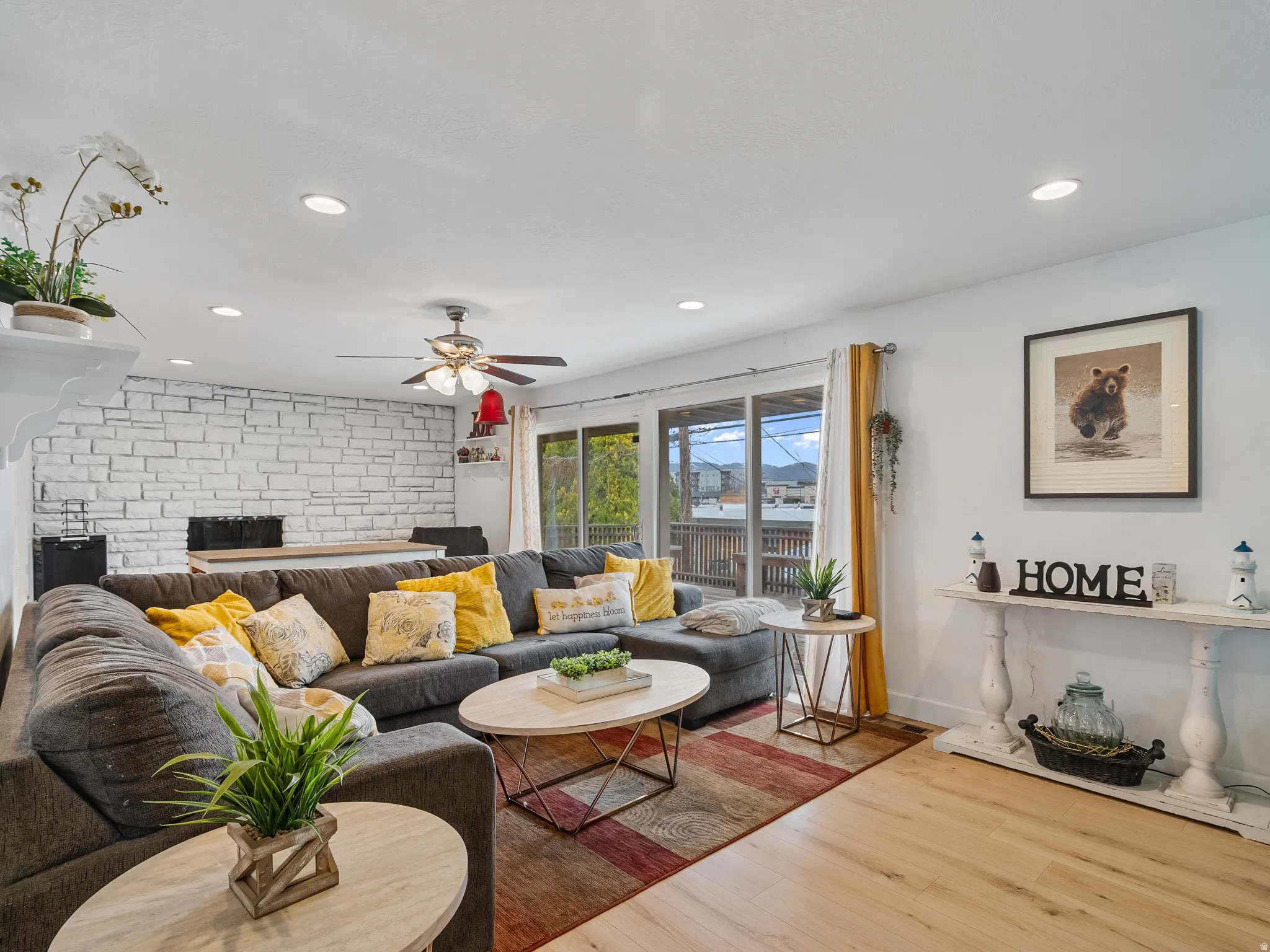 Living room with wood finished floors, a brick fireplace, recessed lighting, and ceiling fan