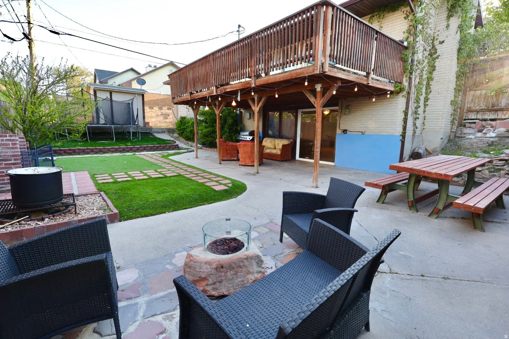 View of patio with a wooden deck, a trampoline, outdoor lounge area, and area for grilling