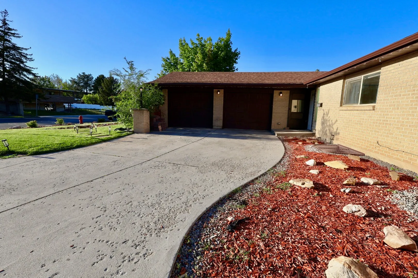 View of side of home featuring an attached garage, concrete driveway, and brick siding