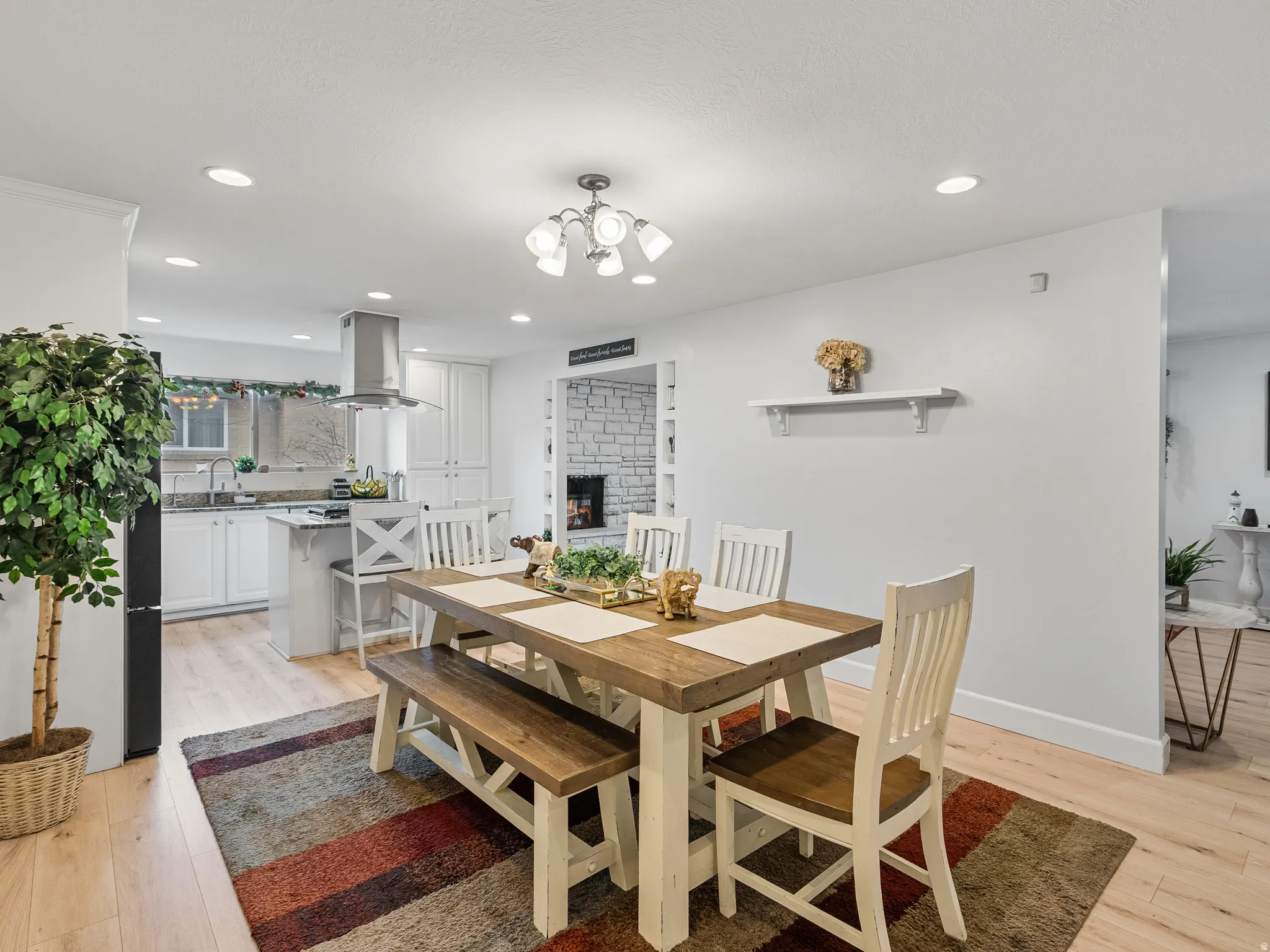Dining space with light wood-type flooring, a chandelier, and a brick fireplace