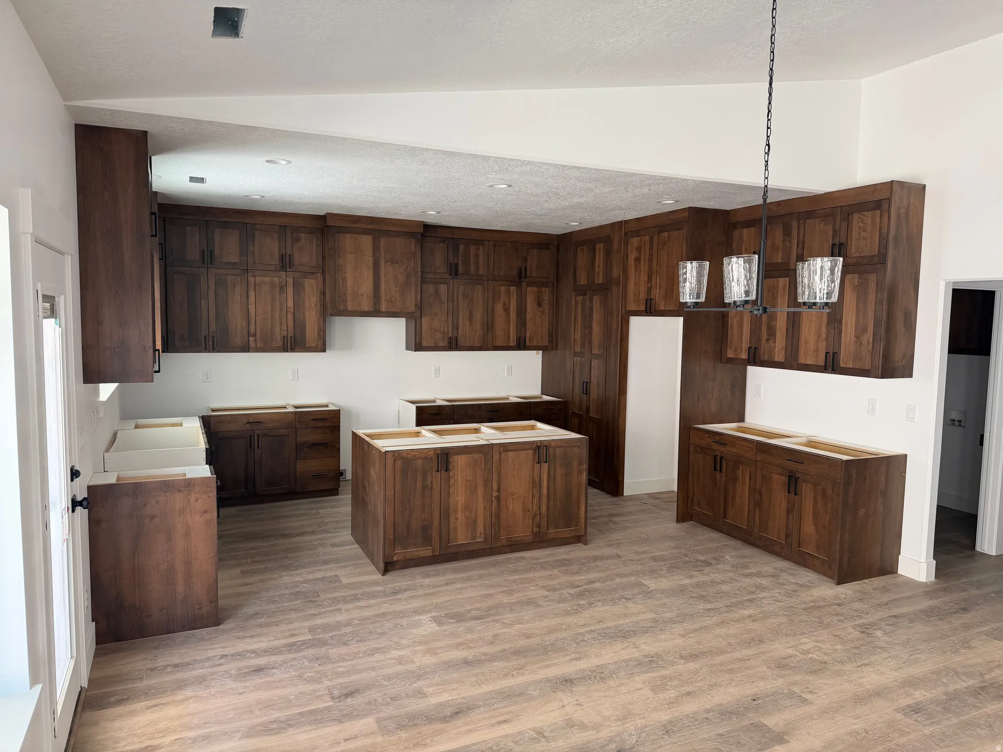 Kitchen featuring a center island, dark wood finish cabinetry, pendant lighting, and light wood finished floors