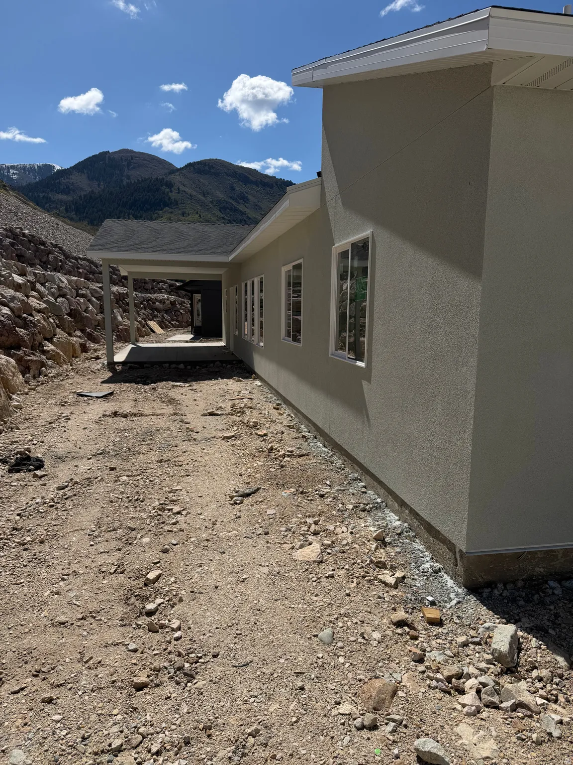 View of side of property with a mountain view, stucco siding, and a patio