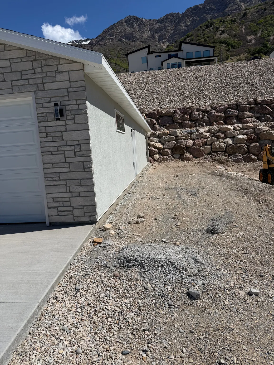 View of side of property with stone siding, a mountain view, and a garage