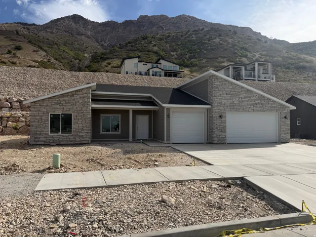 View of front facade with concrete driveway, stone siding, an attached garage, a mountain view, and covered porch