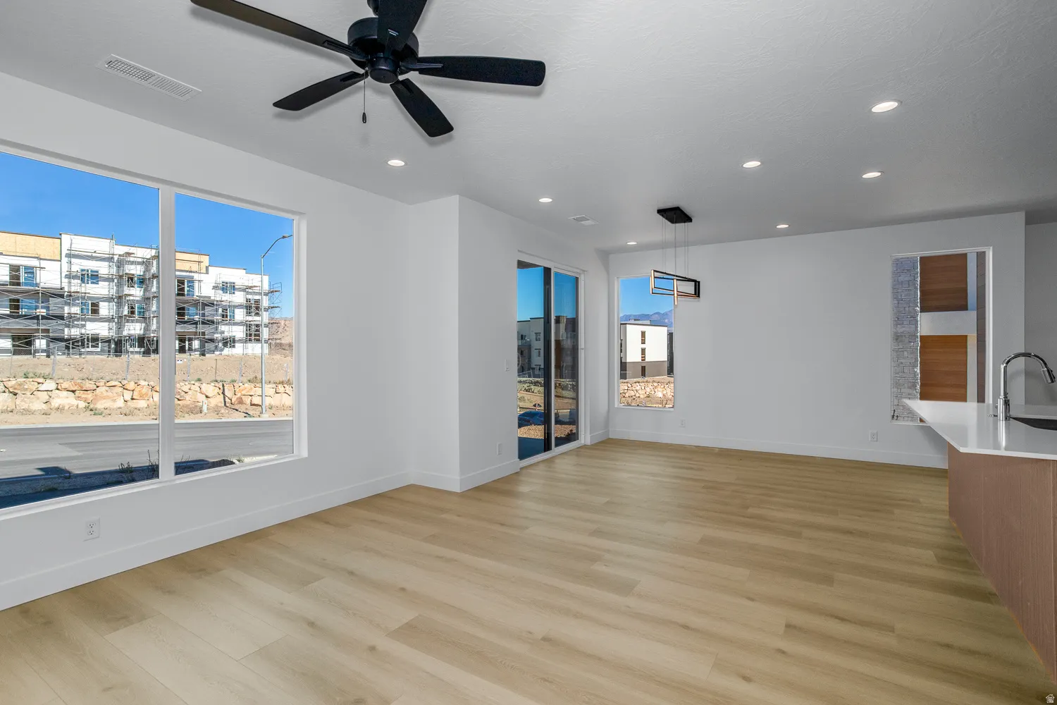 Empty room with light wood-type flooring, ceiling fan, healthy amount of natural light, and recessed lighting