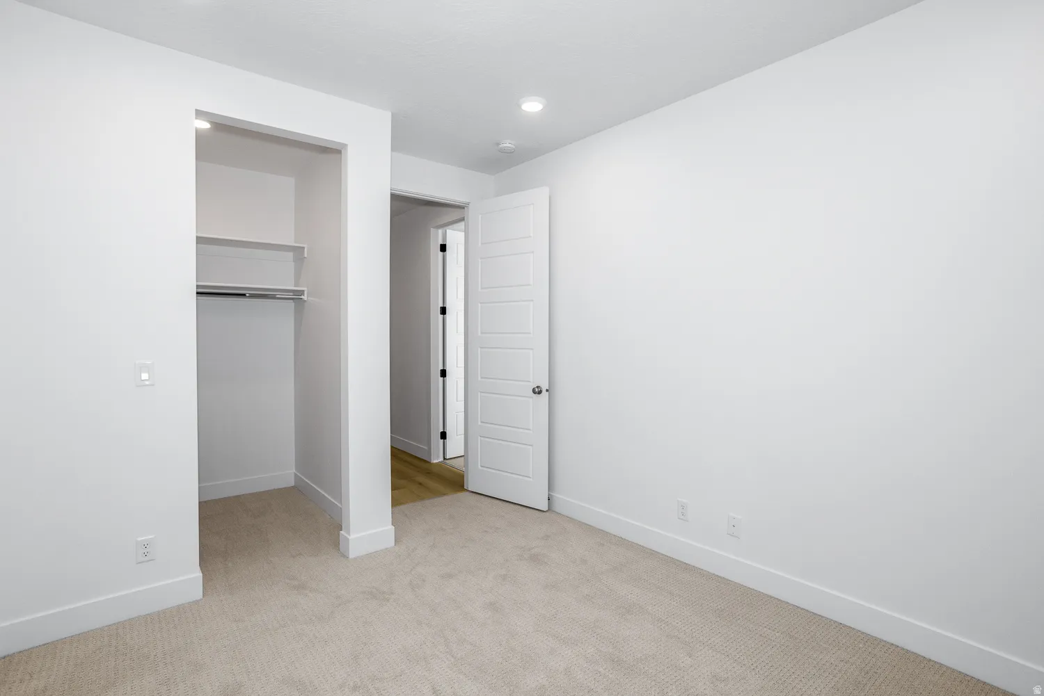 Unfurnished bedroom featuring a walk in closet, light carpet, and recessed lighting