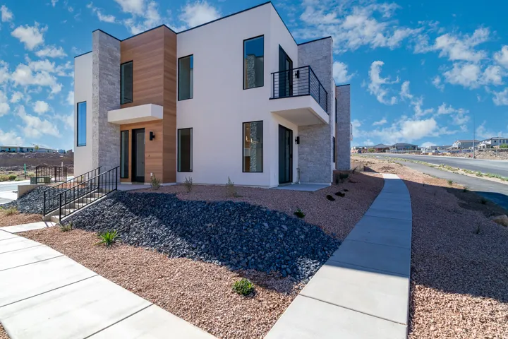 View of front of property with stone siding, stucco siding, a balcony, and a residential view