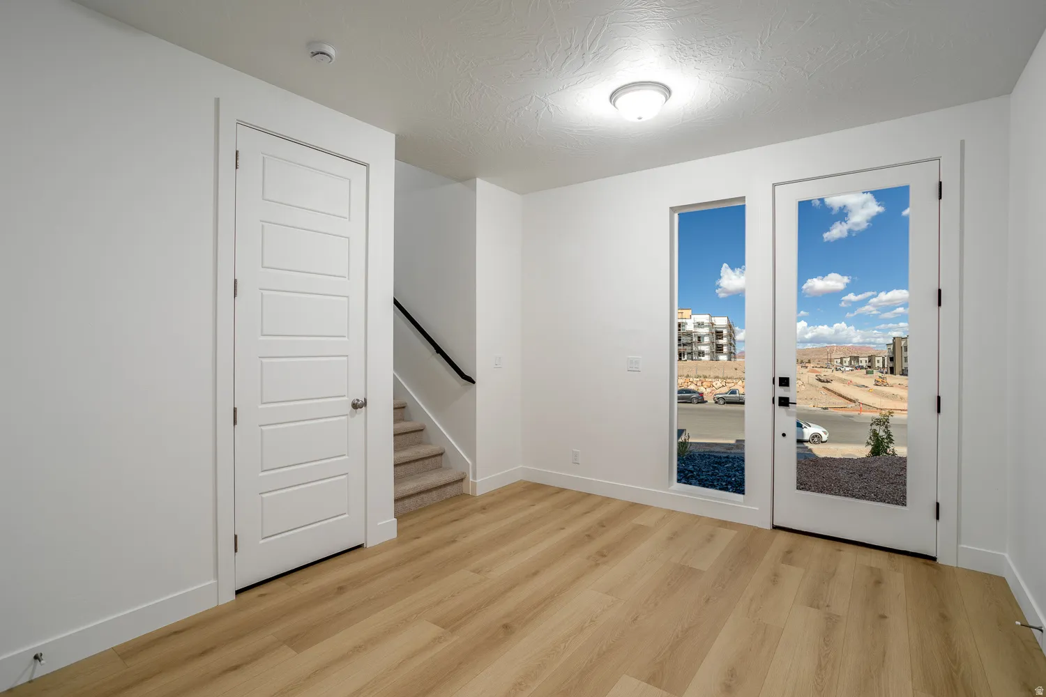 Unfurnished room featuring light wood-style flooring and a textured ceiling