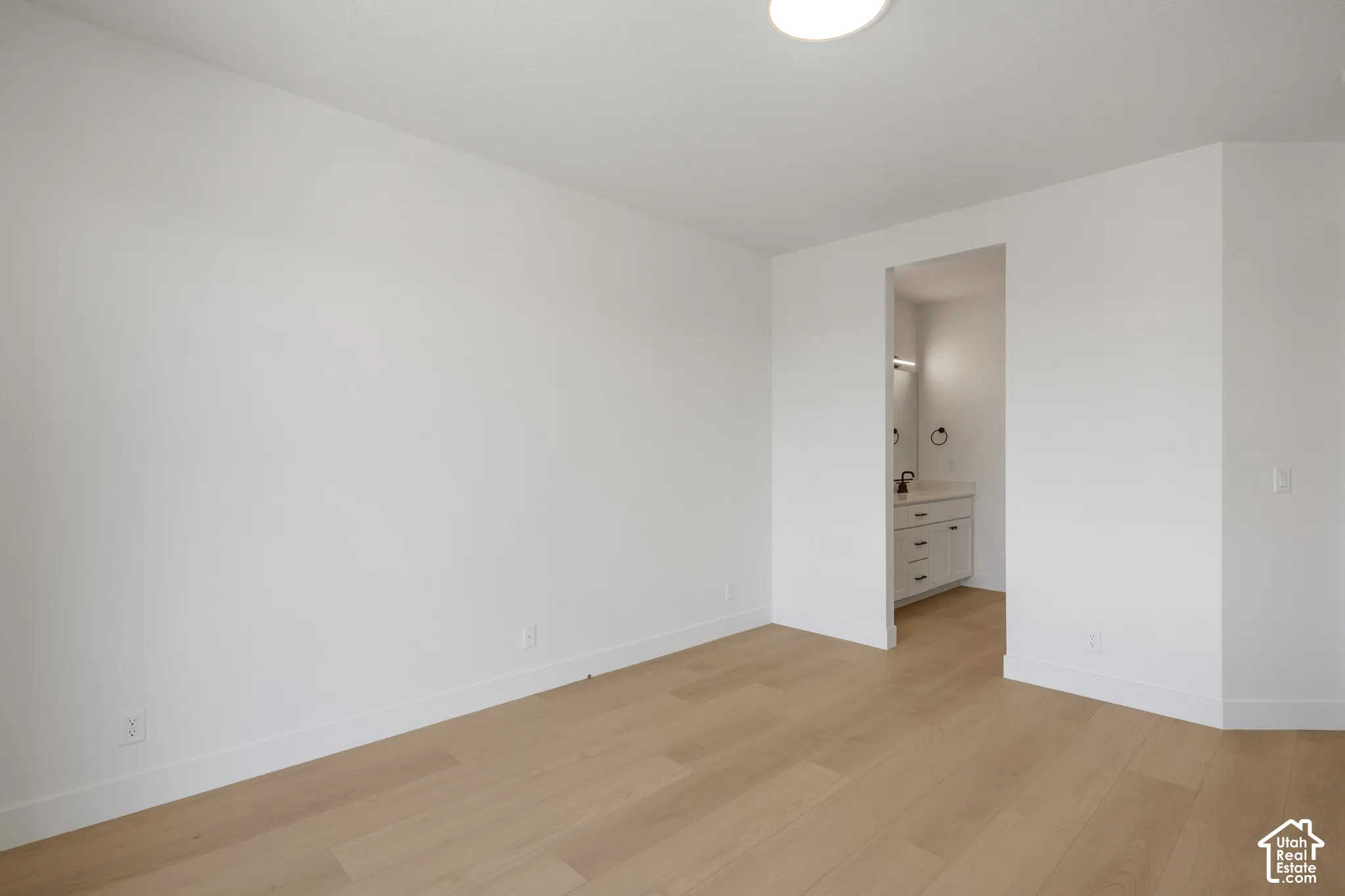 Interior space featuring light wood-finish flooring, smooth white walls, and a recessed ceiling lighting fixture