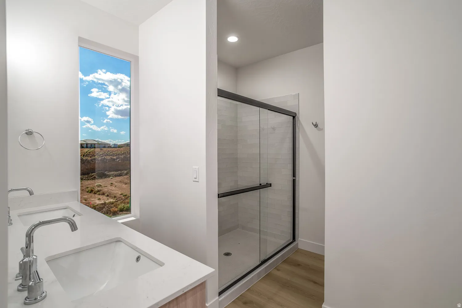 Bathroom featuring double vanity, light wood-style floors, a stall shower, and recessed lighting