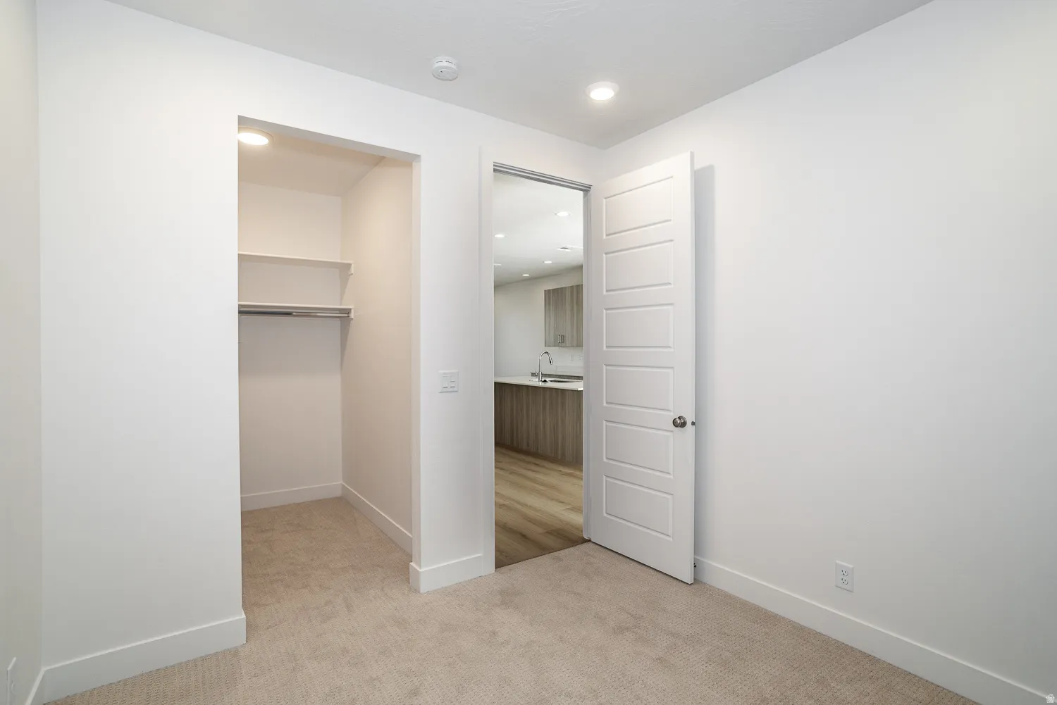 Unfurnished bedroom with a spacious closet, light colored carpet, and recessed lighting