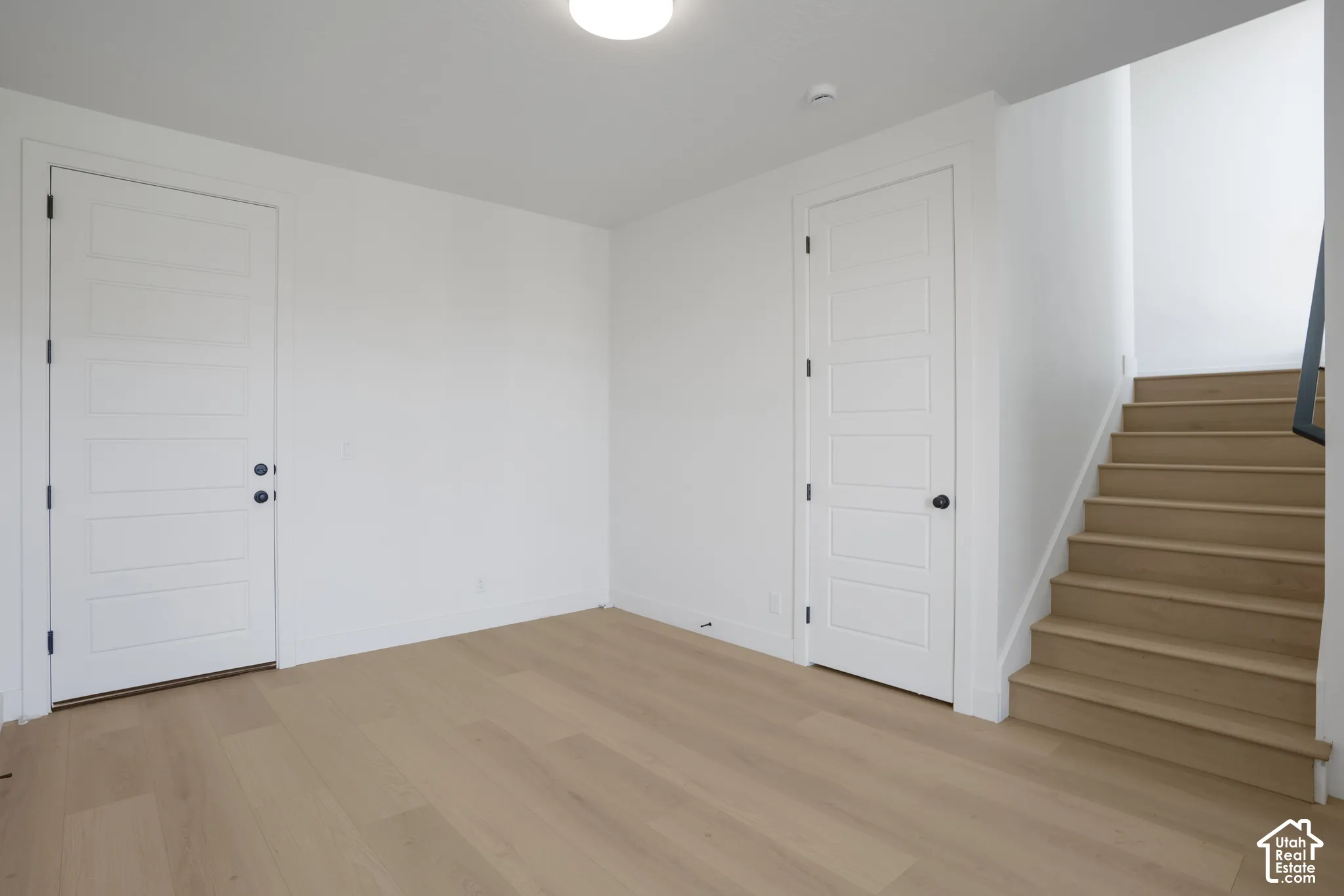 Five-panel interior doors, light wood-finish flooring, and a staircase featuring coordinating wood-finish treads