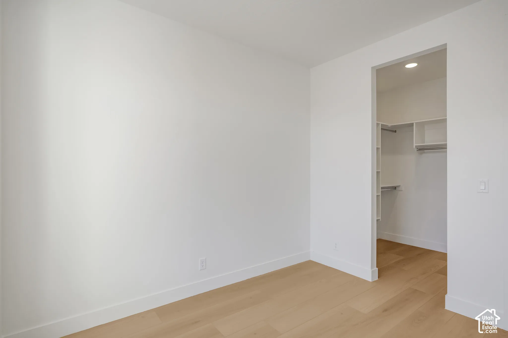 Neutral interior featuring wood-finish flooring and a walk-in closet with built-in shelving