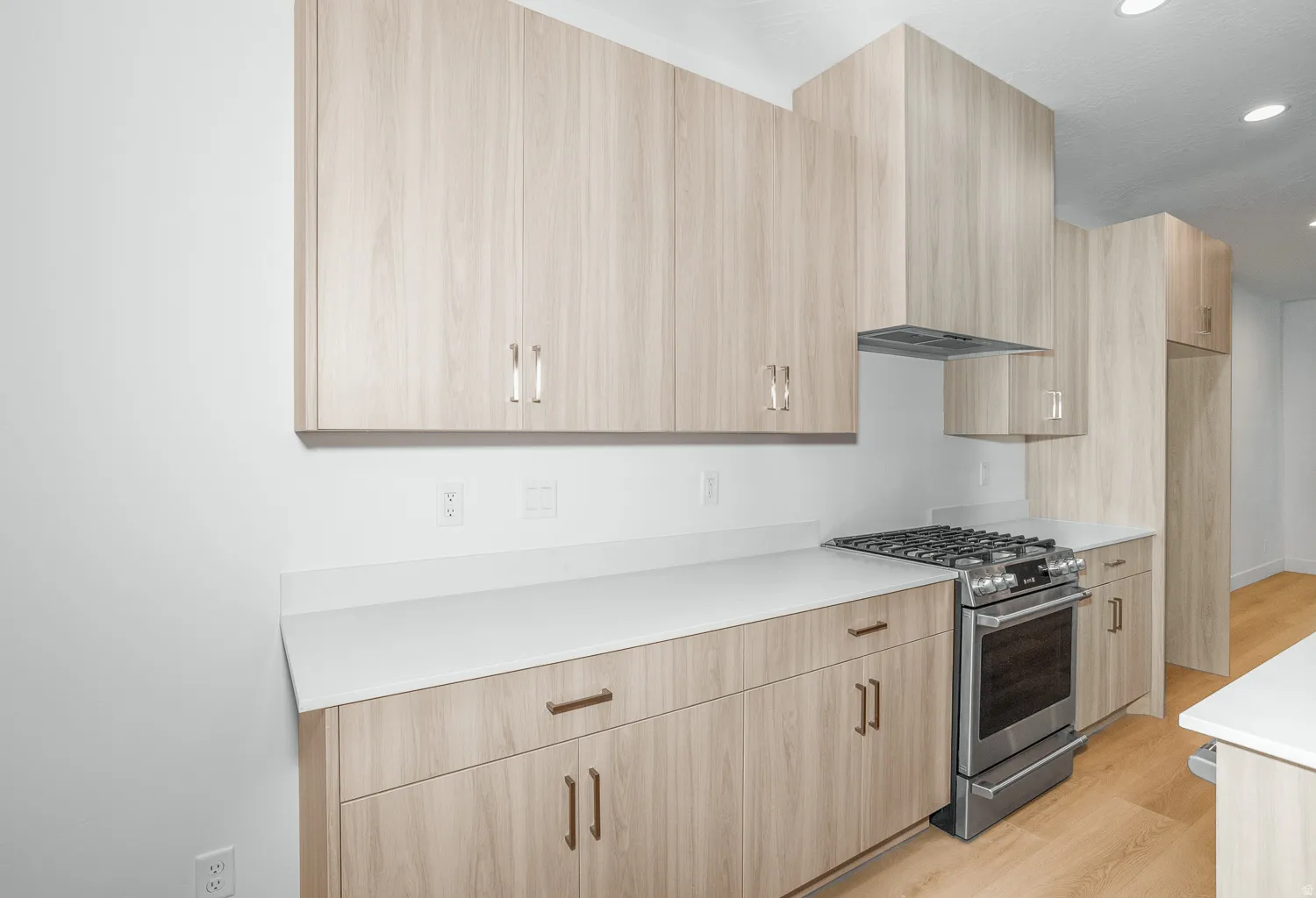 Kitchen with stainless steel gas range oven, modern cabinets, light wood finish cabinetry, and recessed lighting