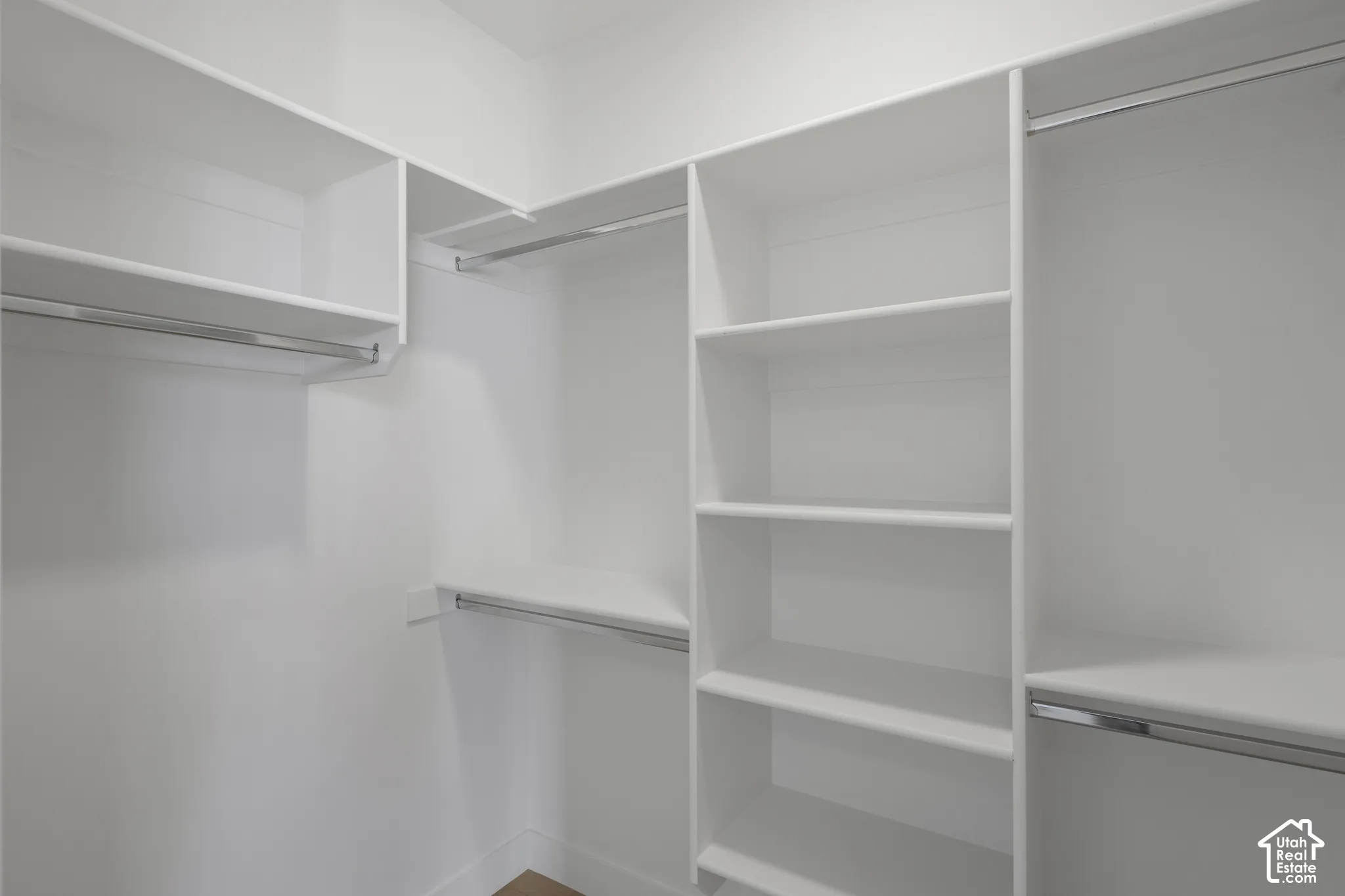 Custom walk-in closet featuring white built-in shelving, multiple tiers of storage, and integrated metal clothing rods