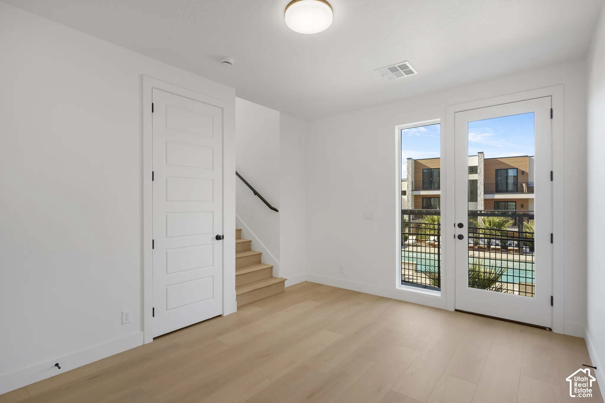 Light-filled space featuring wood-finish flooring, a five-panel interior door, flush-mount ceiling lighting, and a glass-paneled exterior door with side window
