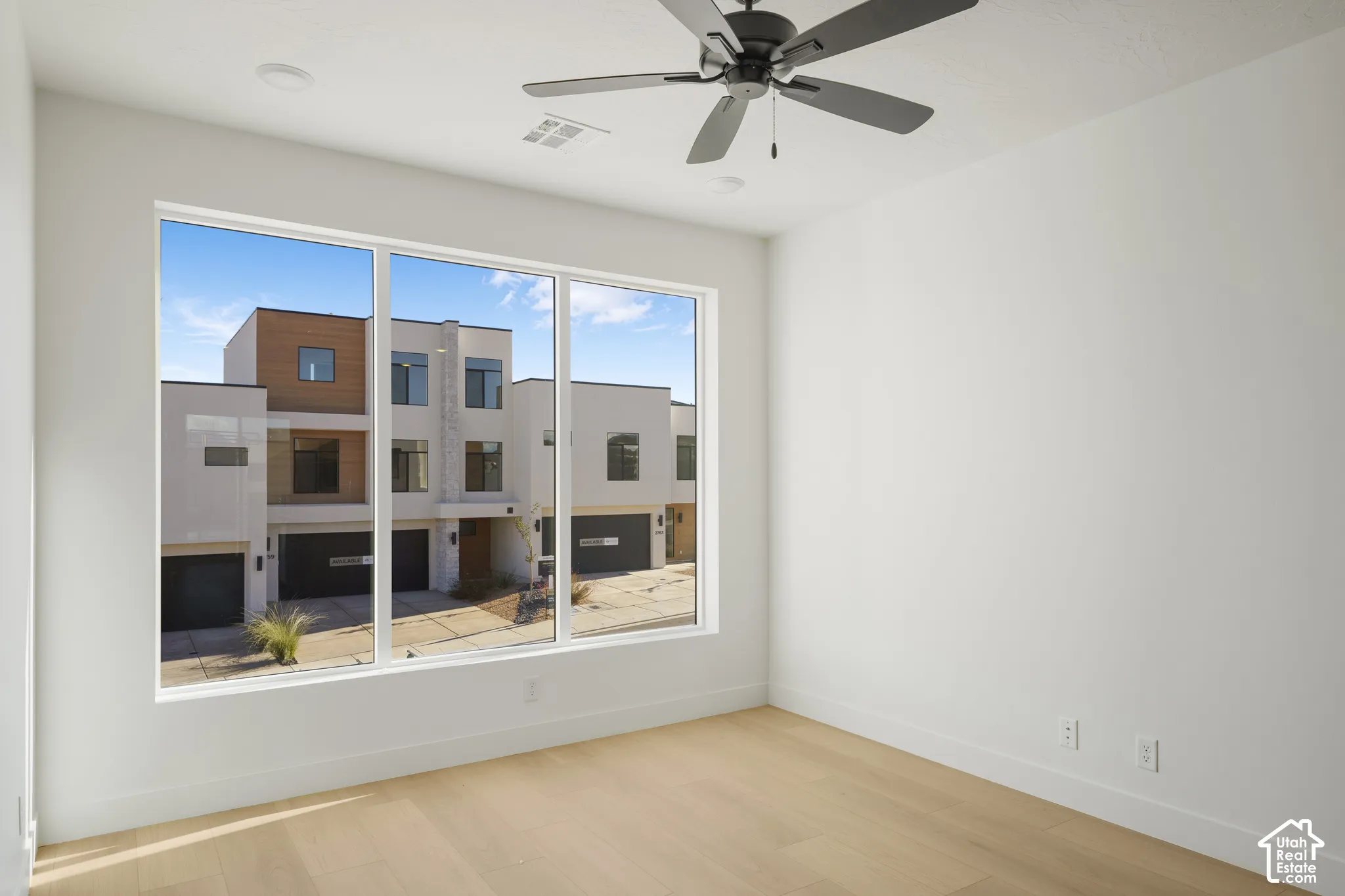 Expansive window with multi-pane configuration, light-toned wood-finish flooring, and ceiling-mounted fan with integrated lighting