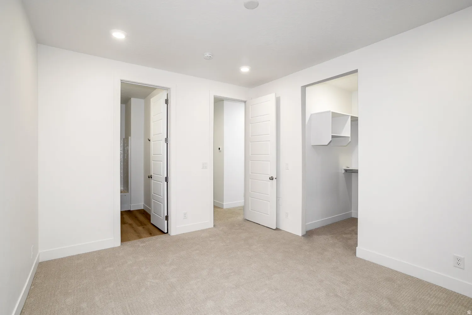 Unfurnished bedroom featuring a walk in closet, light colored carpet, and recessed lighting