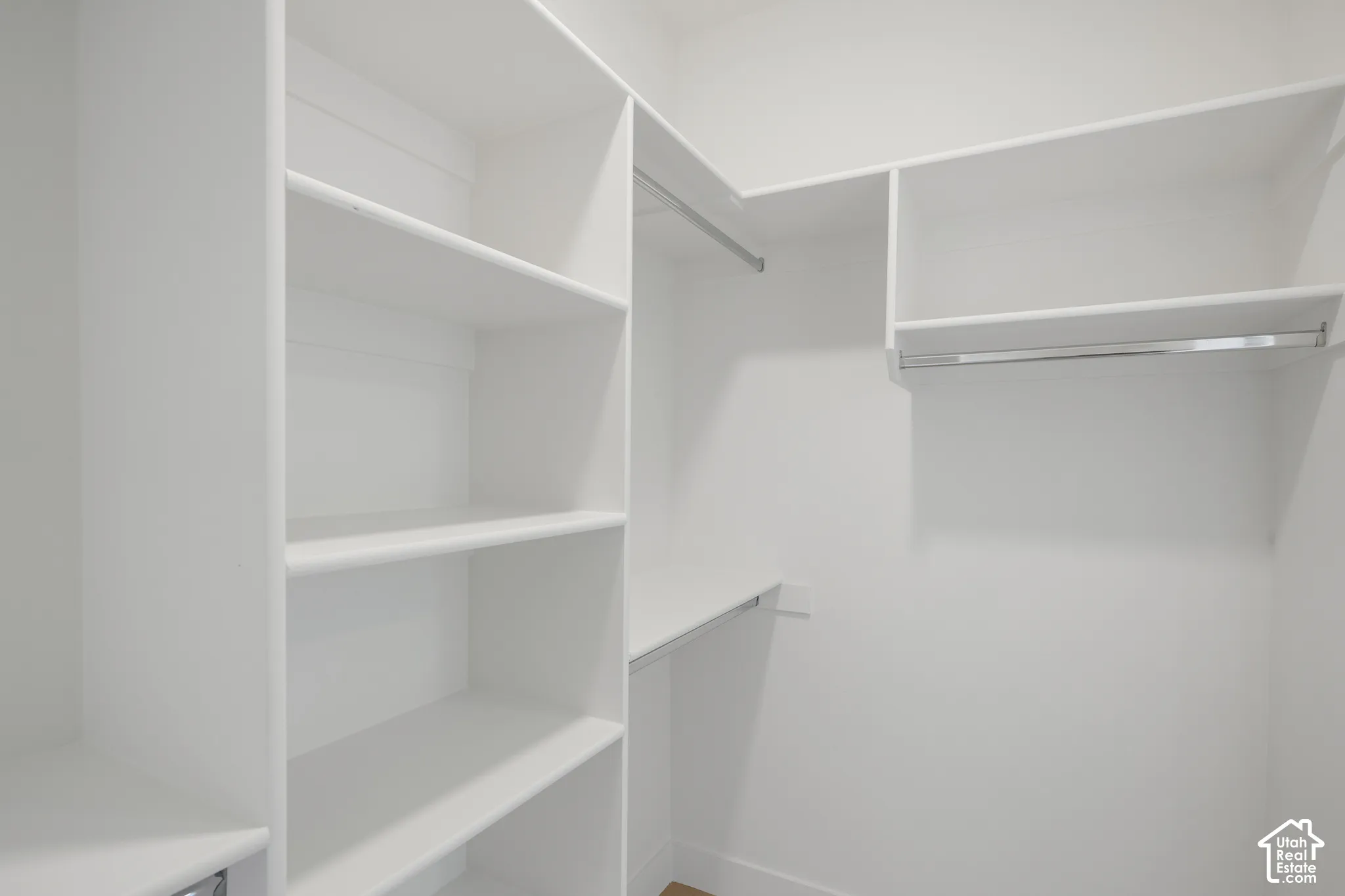 Custom reach-in closet featuring white built-in shelving and integrated metal hanging rods