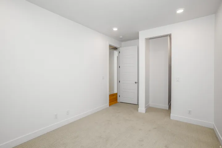 Unfurnished bedroom with light colored carpet and recessed lighting