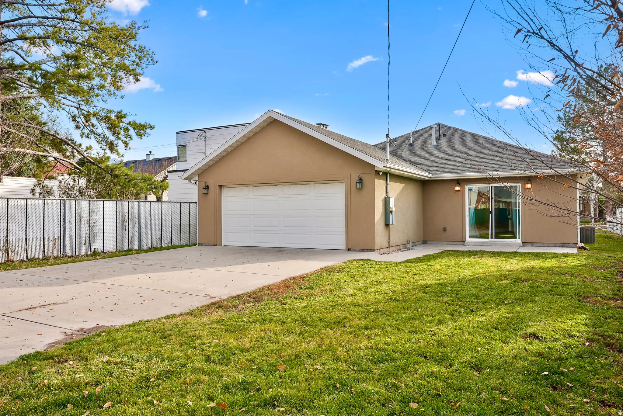 View of front of home with driveway, stucco siding, a shingled roof, an attached garage, and a patio area