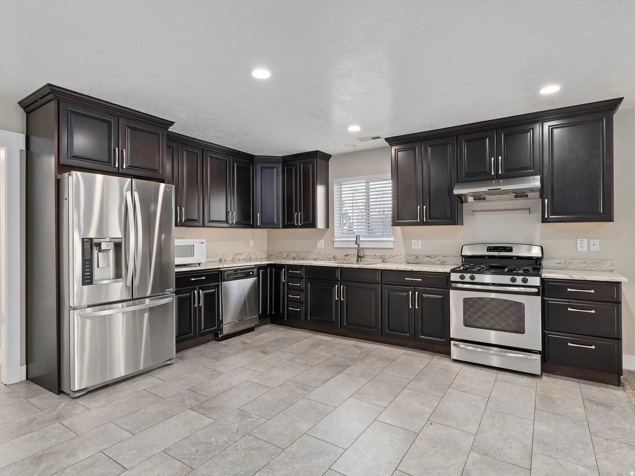 Kitchen featuring stainless steel appliances, light stone countertops, and recessed lighting