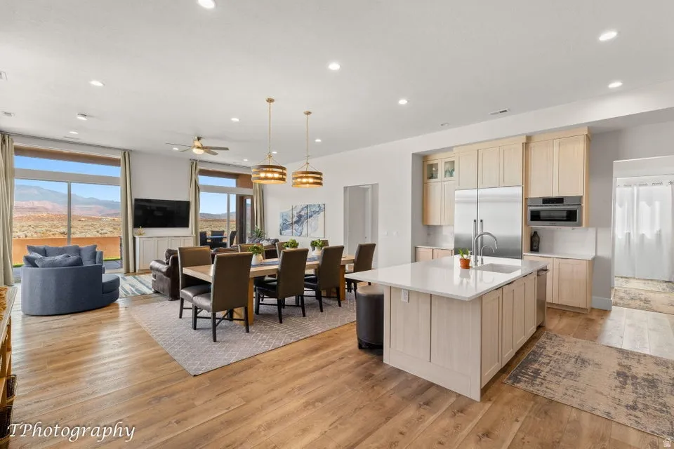 Kitchen featuring light wood finish cabinetry, an island with sink, light wood-type flooring, and open floor plan