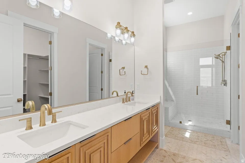 Full bath with a shower stall, double vanity, light tile patterned floors, recessed lighting, and a walk in closet