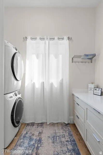 Laundry area featuring stacked washer and dryer and light wood-type flooring