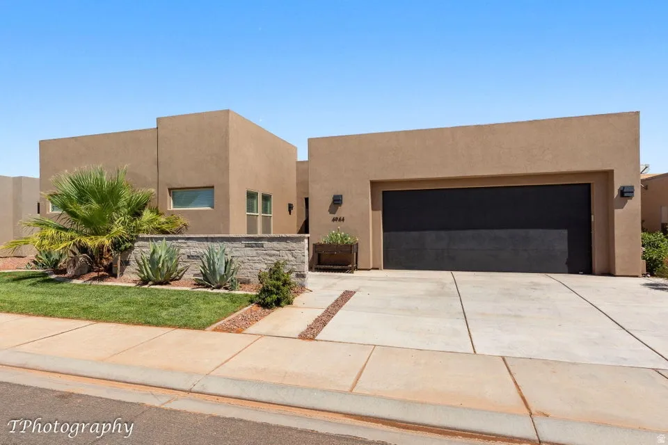 Pueblo-style house featuring stucco siding, driveway, and a garage