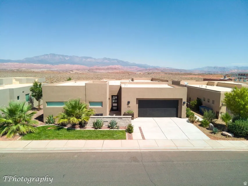 Pueblo revival-style home featuring stucco siding, a mountain view, an attached garage, and driveway