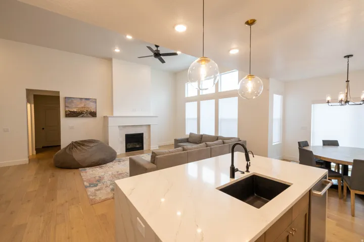 Kitchen with open floor plan, a center island with sink, light wood finished floors, and light stone counters