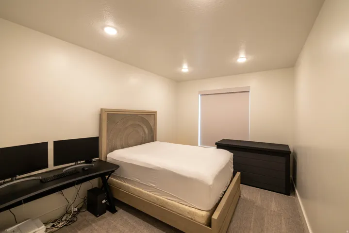 Carpeted bedroom with an office area and recessed lighting