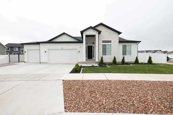 View of front of property with board and batten siding, a garage, concrete driveway, and a gate