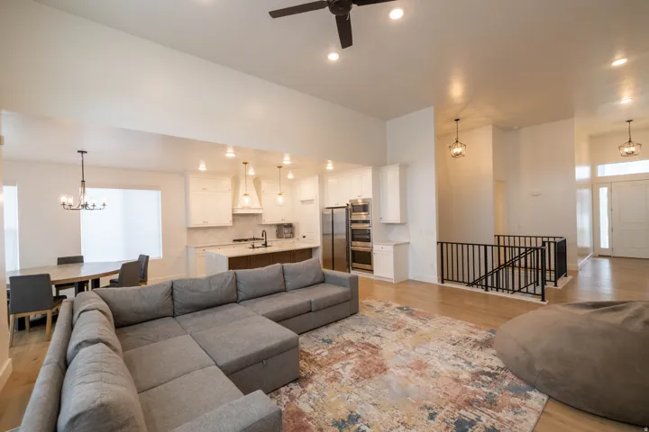 Living room featuring suspended lighting, light wood-type flooring, and a ceiling fan