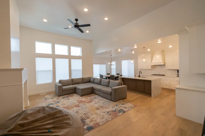 Living area with light wood-style flooring, recessed lighting, ceiling fan, and a high ceiling