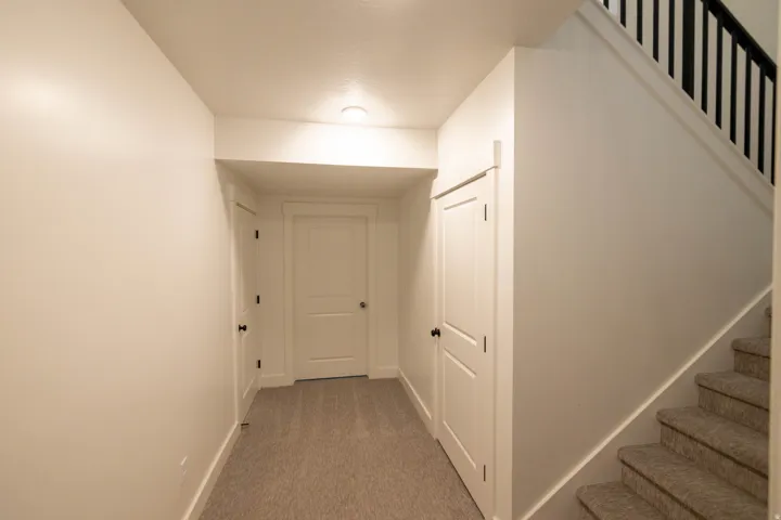 Corridor featuring stairway and light colored carpet