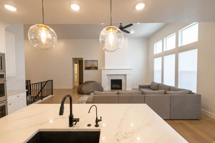 Kitchen featuring light wood-type flooring, open floor plan, white cabinets, light stone counters, and a high ceiling